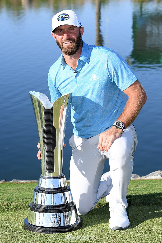 达斯汀·约翰逊高举奖杯，灿烂笑容与银色奖杯在阳光下交相辉映