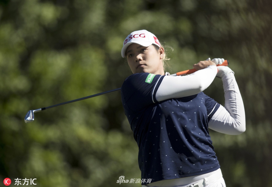 莱克西·汤普森在佛罗里达明媚阳光下,神情专注地挥杆,白色上衣与绿茵球场形成鲜明对比