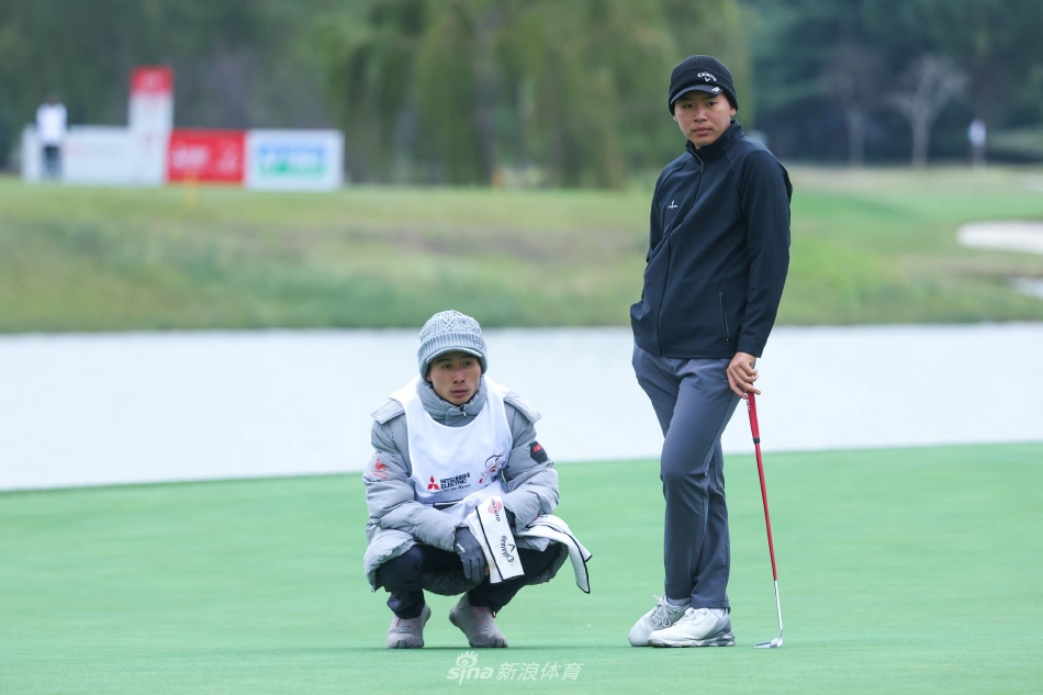 夕阳余晖洒在果岭上，球员与球童并肩观察推击线路，影子被拉得很长，画面温馨而专注。