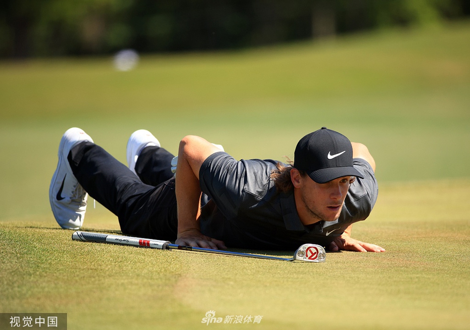 沙坑救球：球员在果岭边的沙坑中击球，沙粒飞扬的瞬间展现了高尔夫比赛中处理困难球位的力量与技巧。