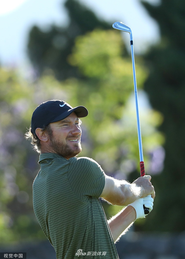 吴阿顺在果岭旁冷静观察推杆线路，他神情专注地蹲下身，仔细评估草纹与坡度。