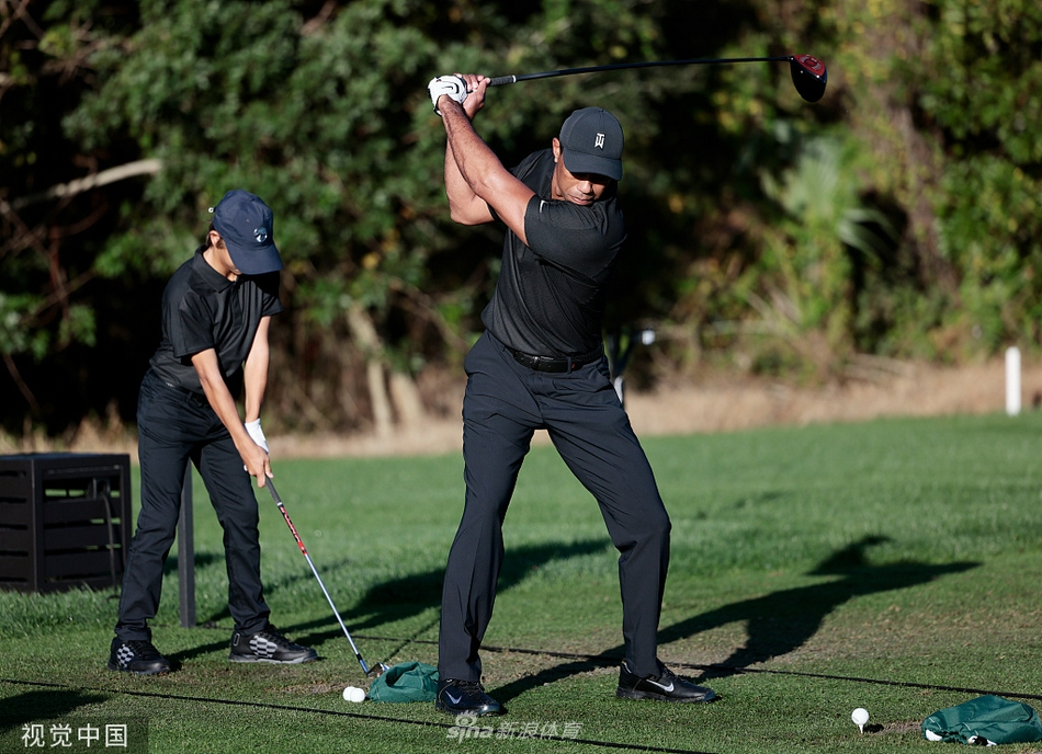 查理·伍兹全神贯注推杆，父亲泰格在身后静静观察目光中充满期许