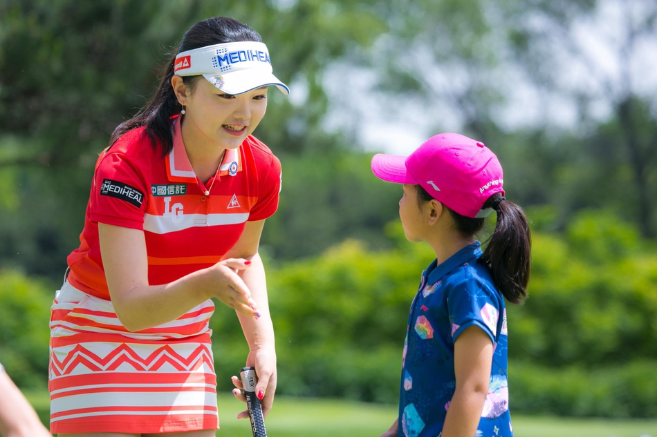 刘国梁弯腰与女儿刘宇婕亲切交谈,手指向球场方向,仿佛在讲解比赛策略