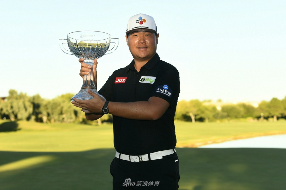 任成宰高举冠军奖杯,身后TPC萨姆林球场的夕阳为他披上金色光芒