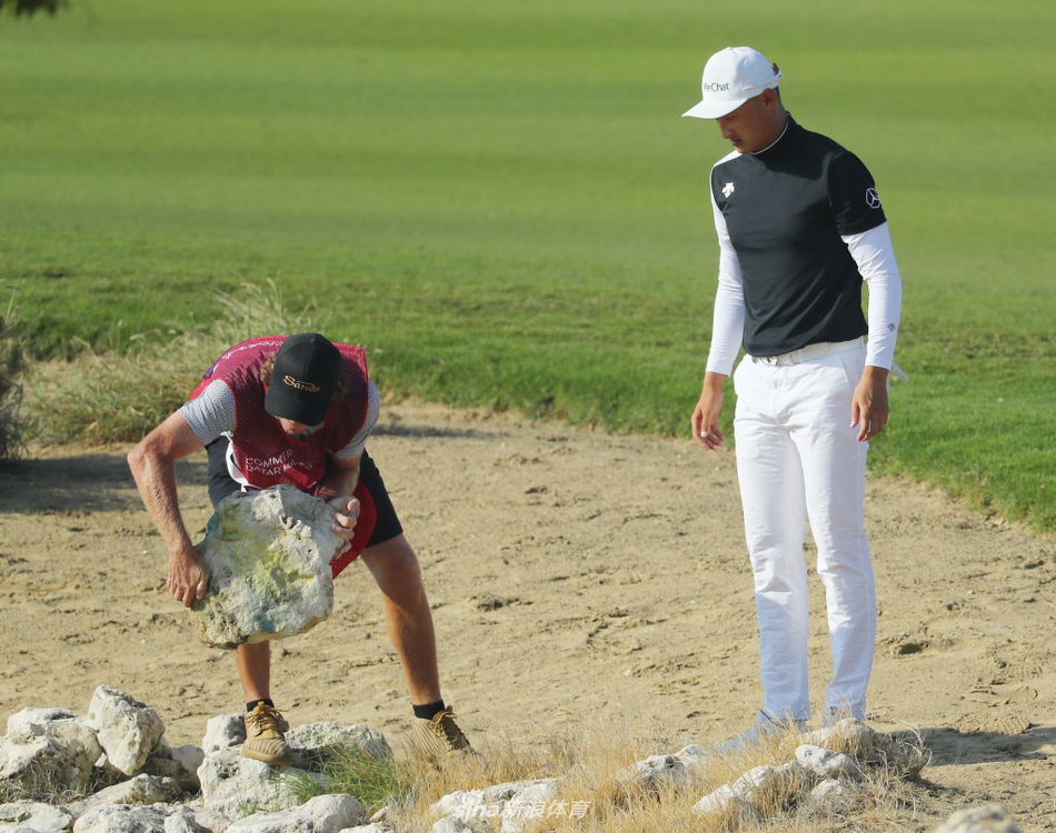 李昊桐眉头紧锁，在巨大的沙坑旁审视球位，身后的沙丘在日光下投下漫长阴影。