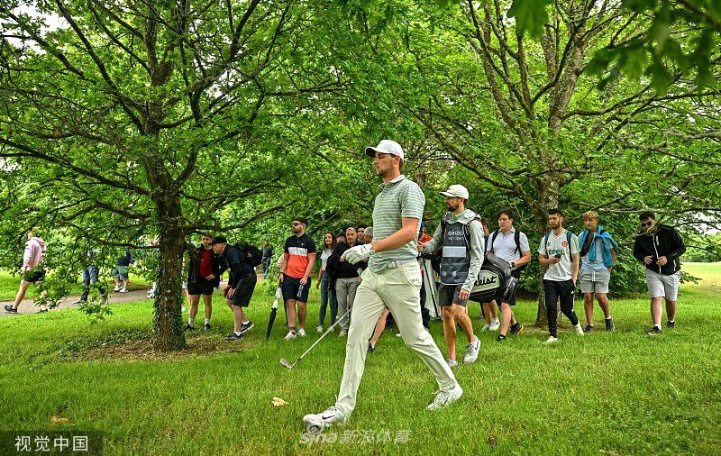 冠军梅龙克高举爱尔兰公开赛银质奖杯，阳光洒满脸庞，身后是挥舞旗帜的欢庆观众与连绵的赛事帐篷