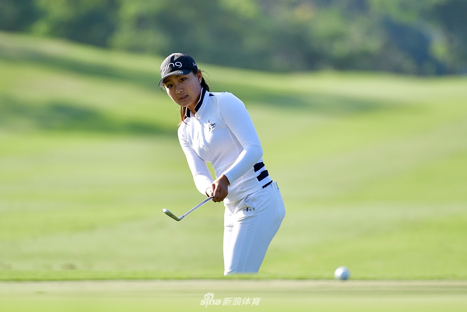 彭婕优雅挥杆瞬间，白色球帽下神情专注，阳光勾勒出流畅的击球弧线。