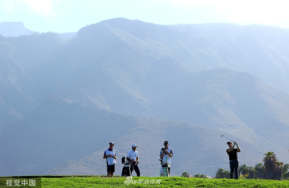 西班牙球员拉波塔在果岭边凝神观察推杆线路,加那利群岛的蓝天与绿草构成鲜明背景