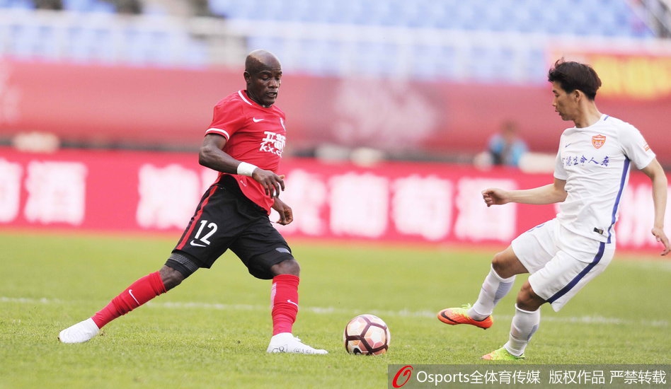 辽足功勋外援詹姆斯在延边队严密防守下，用强壮的身体倚住后卫，奋力将球控制在高高跃起的双腿之间，眼神坚定地寻找出球路线。