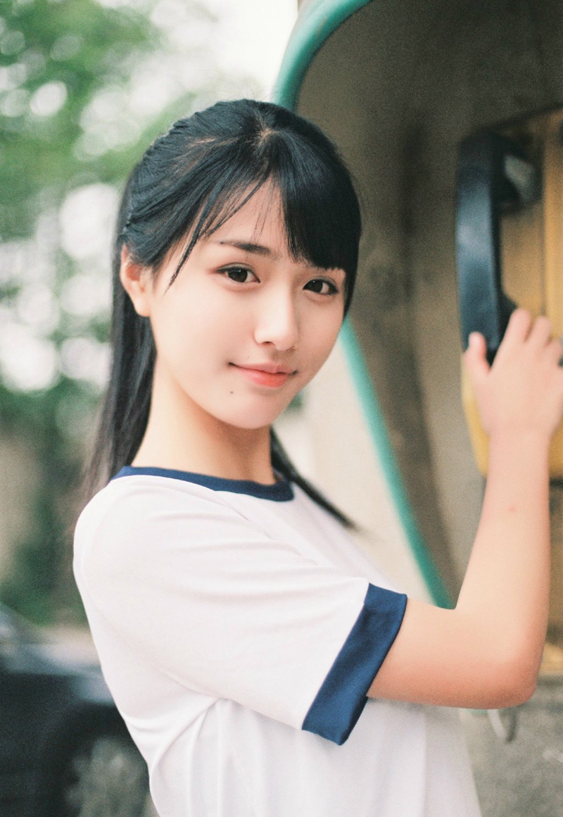 近景镜头下,女孩运动背心的棉质纹理清晰可见,几缕被汗水沾湿的碎发贴在脸颊上,她露出明媚而略带羞涩的笑容,身后是郁郁葱葱的夏日树影