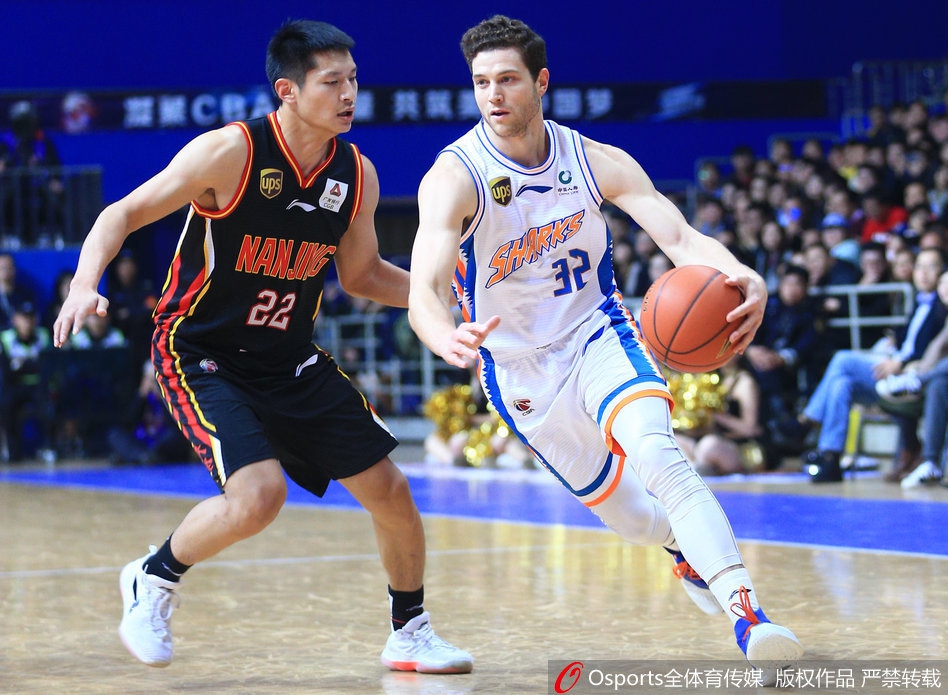 青岛队外援在严密包夹下强行突破，防守球员的手臂几乎缠在他腰间，皮球仍在指尖旋转，瞬间的肌肉对抗凝固在画面里。