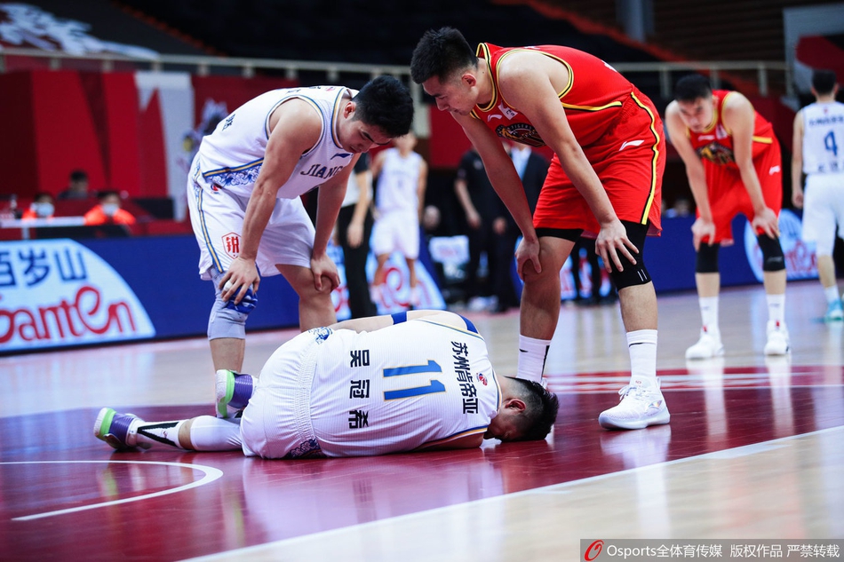 队医拿出喷雾剂，对准吴冠希肿胀的左脚踝进行紧急冷处理，旁边的队友和对手球员都神情凝重地看着这一幕。