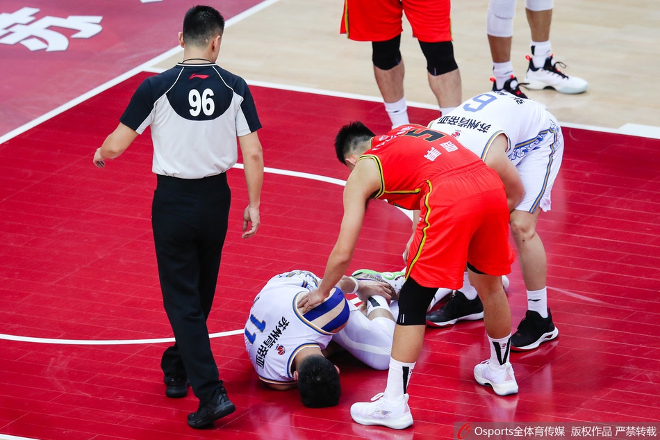 在队友的左右搀扶下，吴冠希勉强站立，受伤的左脚高高抬起不敢着地，他低着头，球衣上沾满了地板上的灰尘。