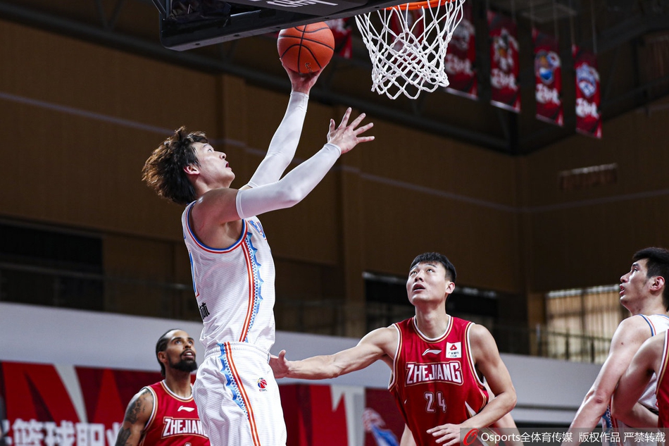 浙江金牛队球员在三人包夹的缝隙中强行起飞上篮，防守者的手臂几乎封住了所有角度，他却在空中利用腰腹力量拉杆，将球送入网窝。