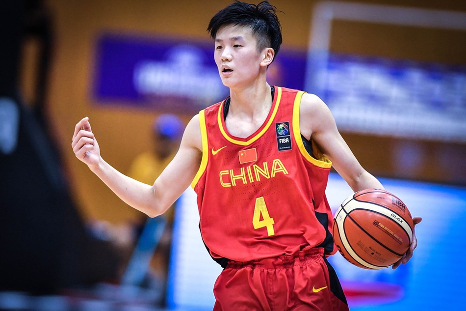 中国队内线球员万济圆在对方多人包夹之下，高高跃起争抢篮板球，展现了她在内线强大的统治力和拼搏精神