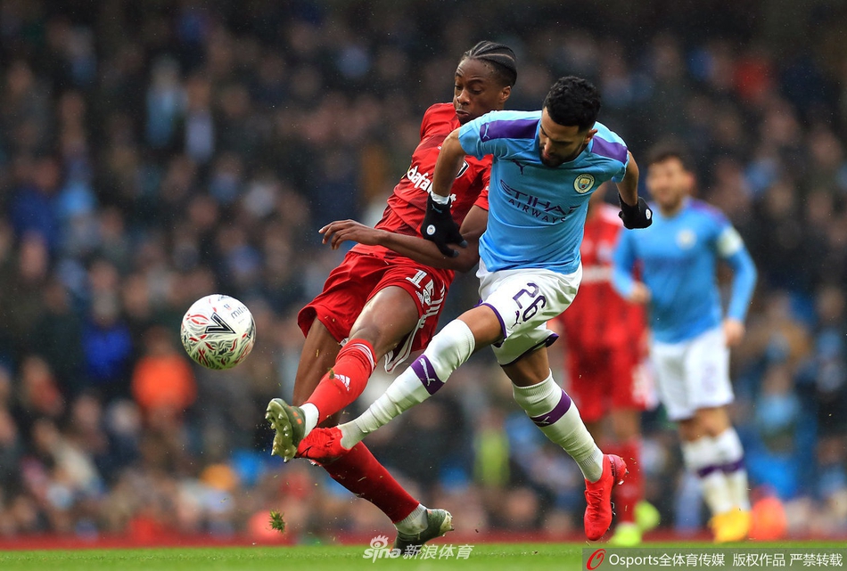 身着天蓝色球衣的曼城球员们围在一起激情庆祝进球，伊蒂哈德球场欢声雷动