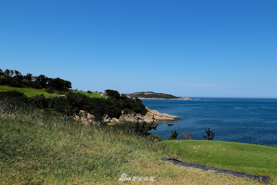 5号洞一隅，球道沿着险峻的悬崖蜿蜒，翠绿的草坪与下方深蓝色的海水形成鲜明对比，仿佛一条通往天际的绿色丝带。