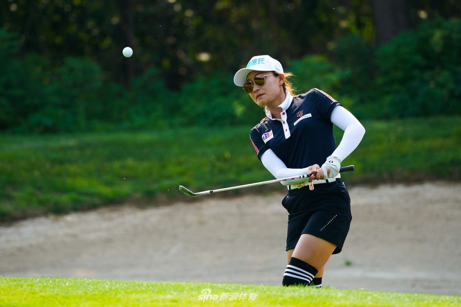 果岭旁，球手半蹲凝神阅读草纹走向，指尖轻触草坪，神情专注如科学家探寻奥秘。