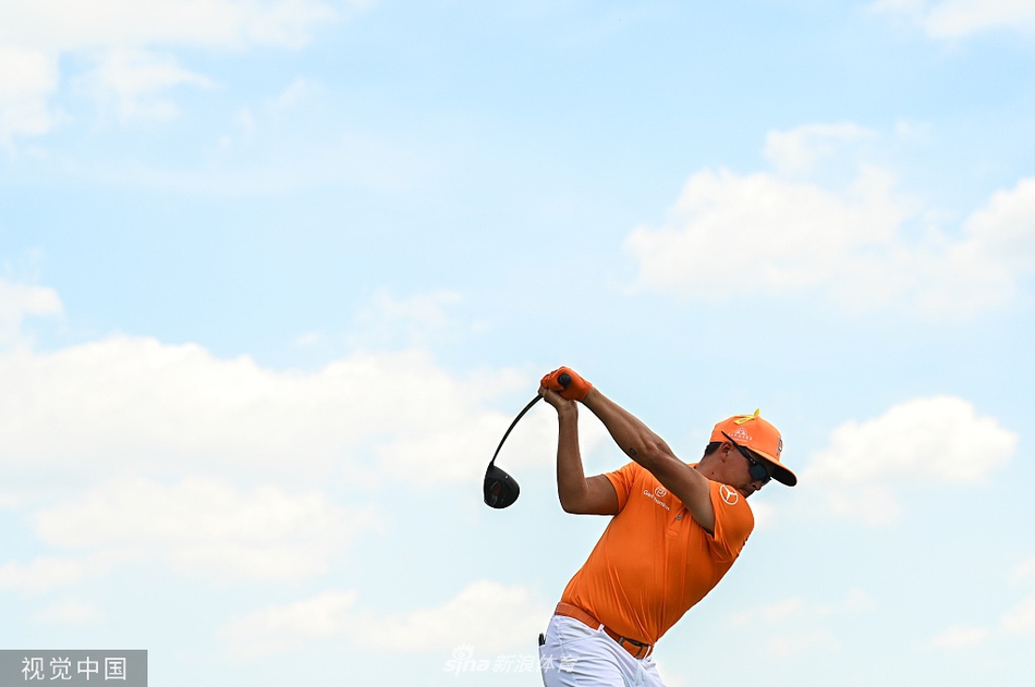 里奇·福勒在球道上观察球路，神情专注，阳光洒在他的橙色上衣上，显得格外醒目。