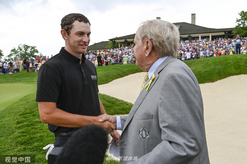 赛事主人杰克·尼克劳斯身着标志性的黄色马球衫，背手伫立在第十八洞果岭边缘，专注而平静地等待着新冠军的诞生。