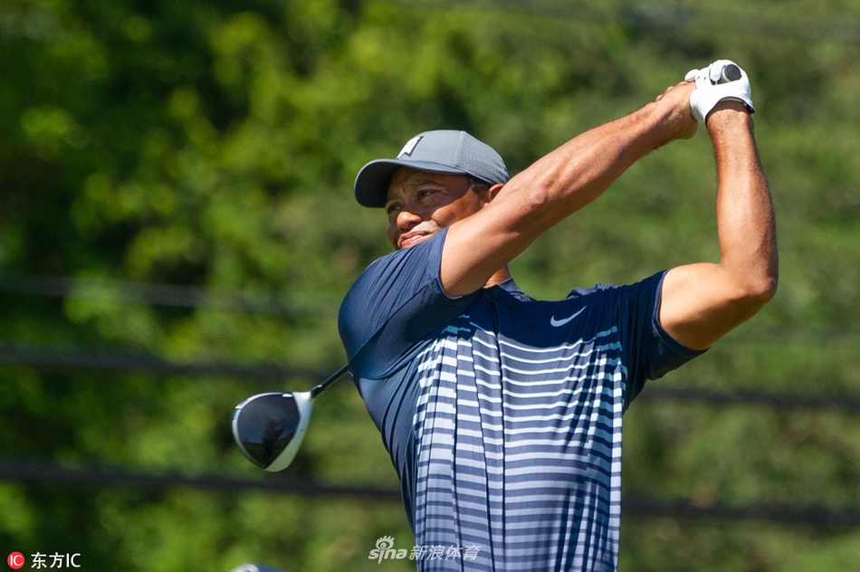 伍兹完成一次有力的开球后，保持收杆姿势，目光锐利地追随着空中小白球的飞行轨迹。