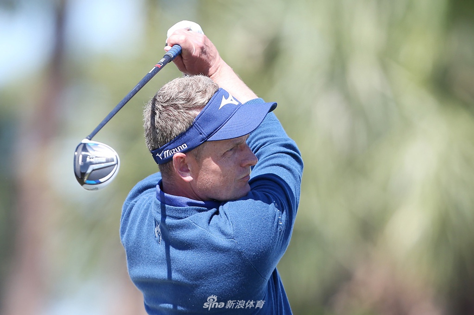 一位球员走入水中准备救球，水面泛起涟漪，背景是绿色的球场和观众，画面充满动感和悬念。