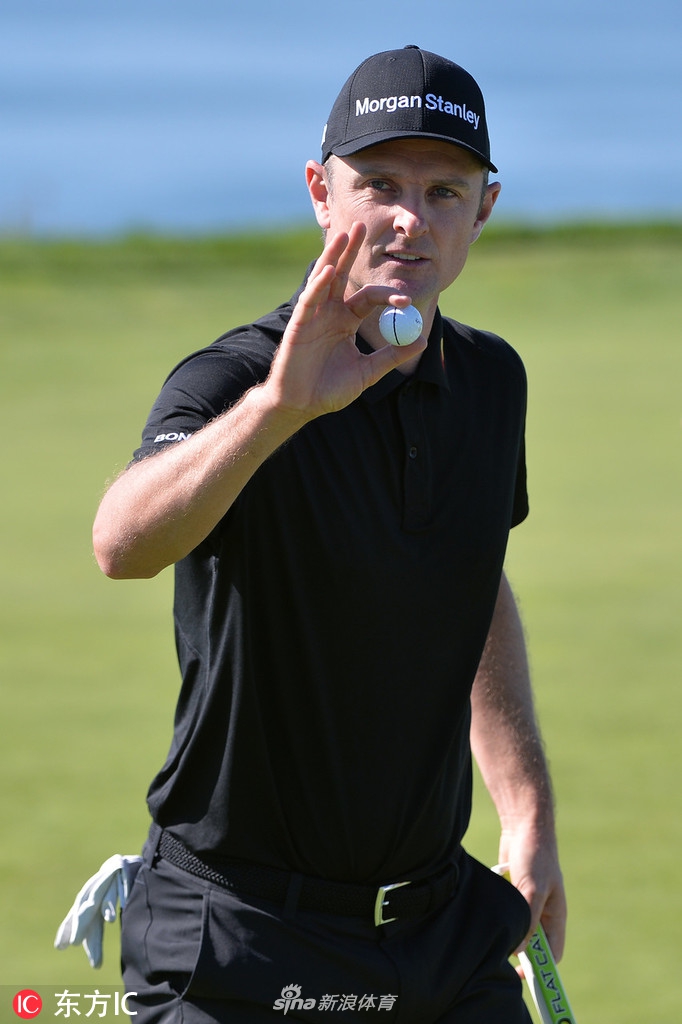 罗里麦克罗伊在果岭边沉稳推杆，凝神关注小白球滚动的路线