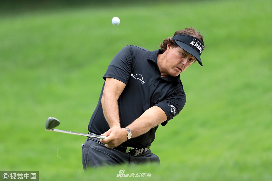 两人在果岭边微笑交流，米克尔森手指远方似乎在讨论策略，轻松的氛围溢于言表