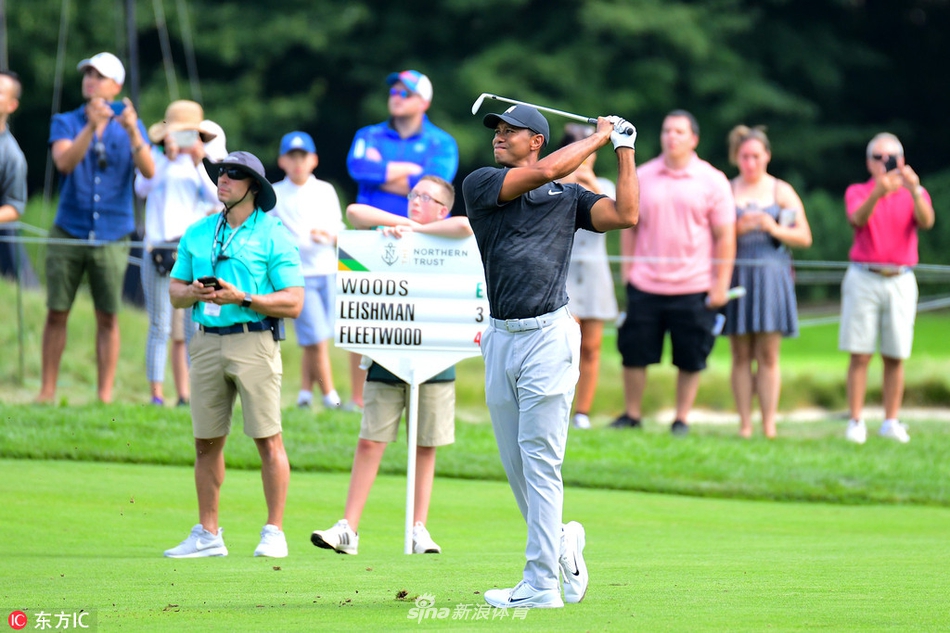 老虎伍兹走向下一个发球台,步伐沉稳,身旁跟随着庞大的观赛人群,彰显其无与伦比的号召力。