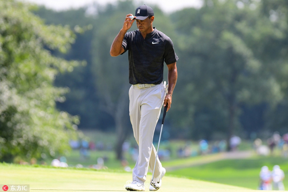 伍兹在球道上打出精准一击,小球在空中划出优美弧线,背景是郁郁葱葱的比赛场地。