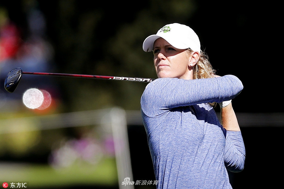 艾米·奥尔森在果岭边凝神观察推杆线路，身后是依云球场著名的湖光山色