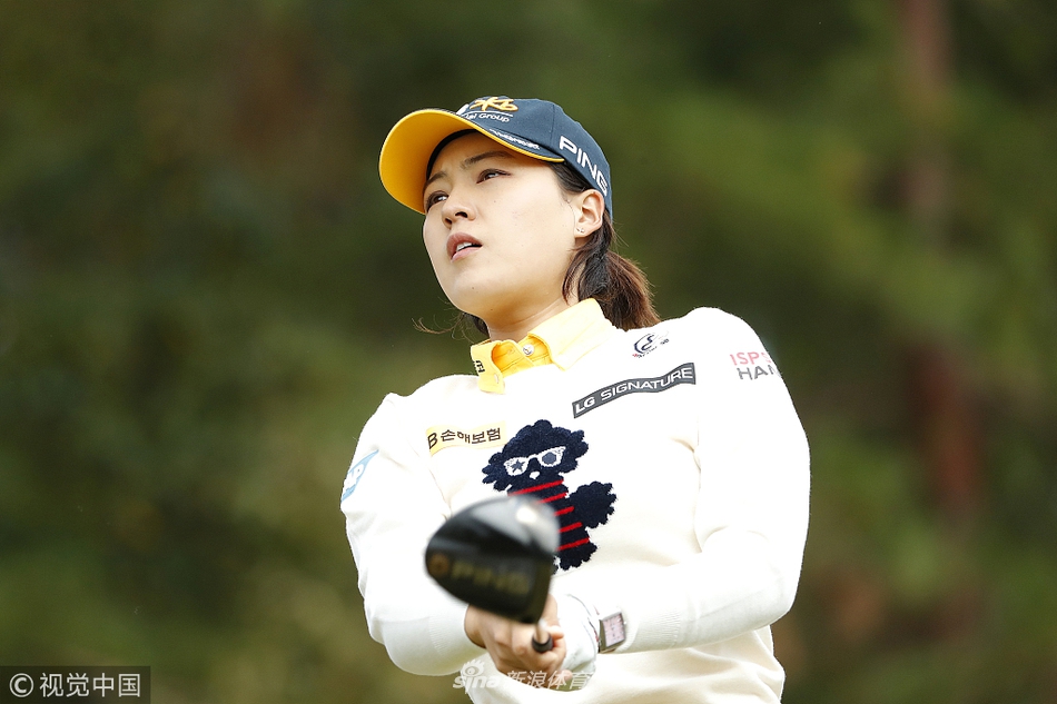 韩国实力球员田仁智在茂密的球场树荫下冷静推杆，专注的神情与宁静的环境形成鲜明对比。