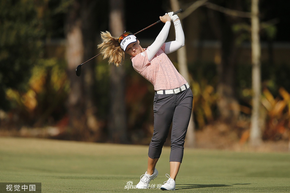 比赛中的金世煐姿态舒展，完成一次标准的收杆动作，背景是郁郁葱葱的锦标赛级球场。