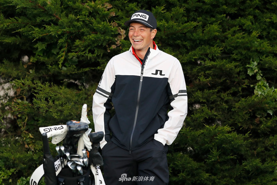 维克多·霍夫兰在练习轮中全力挥杆，背景是圆石滩标志性的海岸线与翻滚的浪花