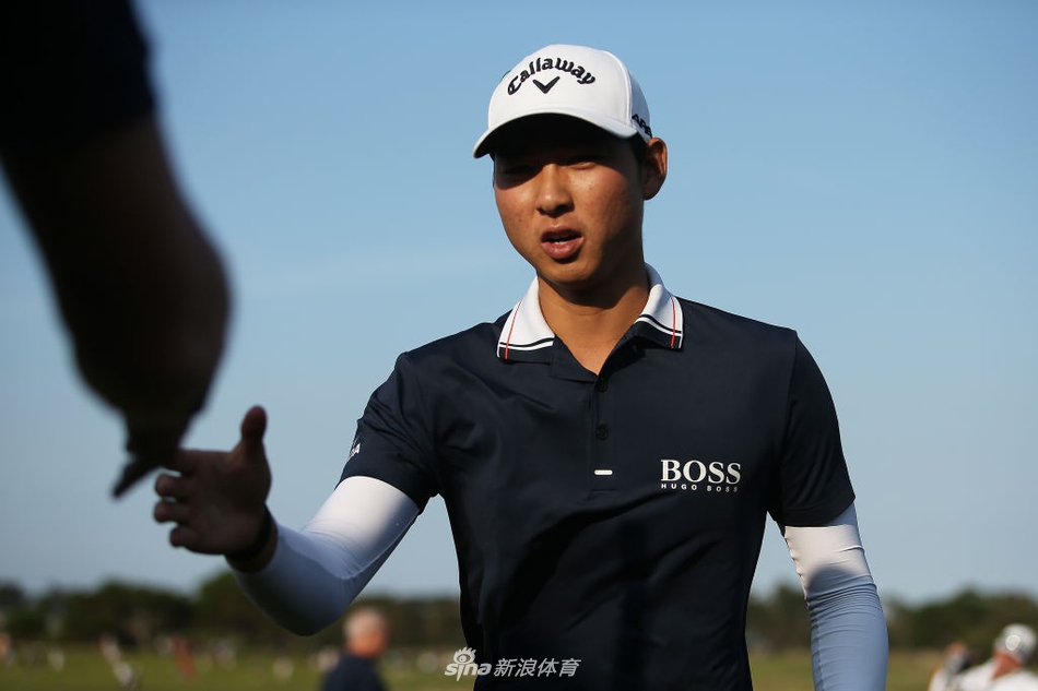 李旻宇在果岭上屈膝仔细观察推杆线路，他紧握推杆，全神贯注于决定胜负的下一击。