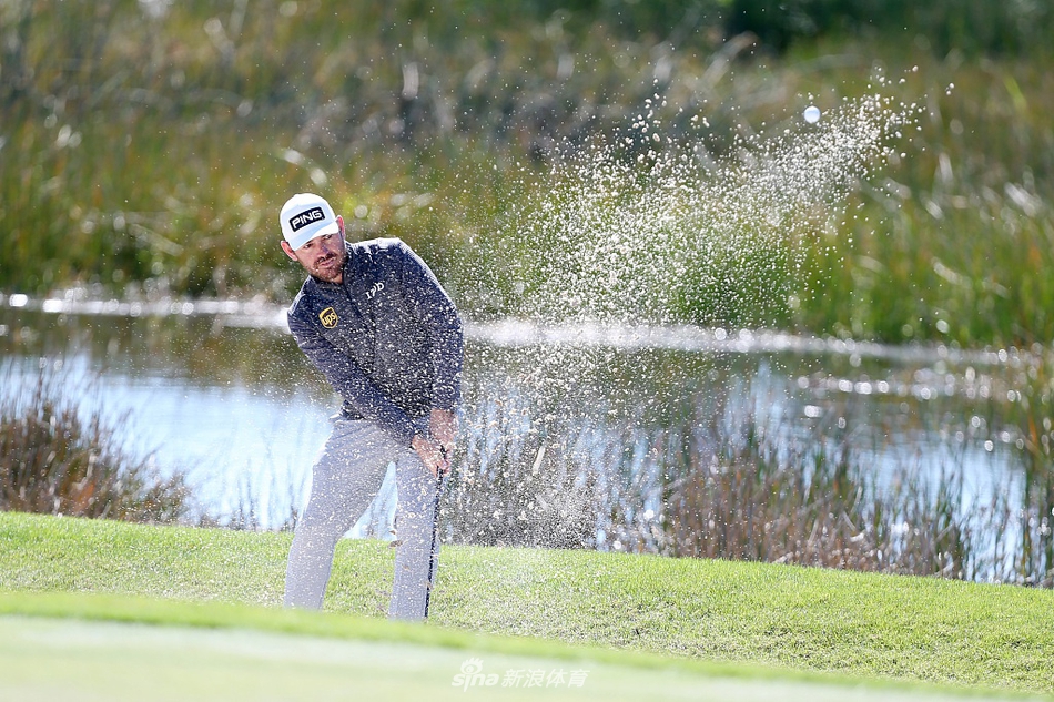 卢克·唐纳德在果岭上仔细研读推杆线路，阳光将他的身影拉长，氛围宁静而专注。