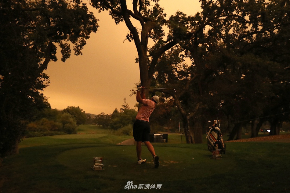 球道旁，一位球手在橙红色的柔和光线下专注于自己的挖起杆击球，周遭异常宁静。