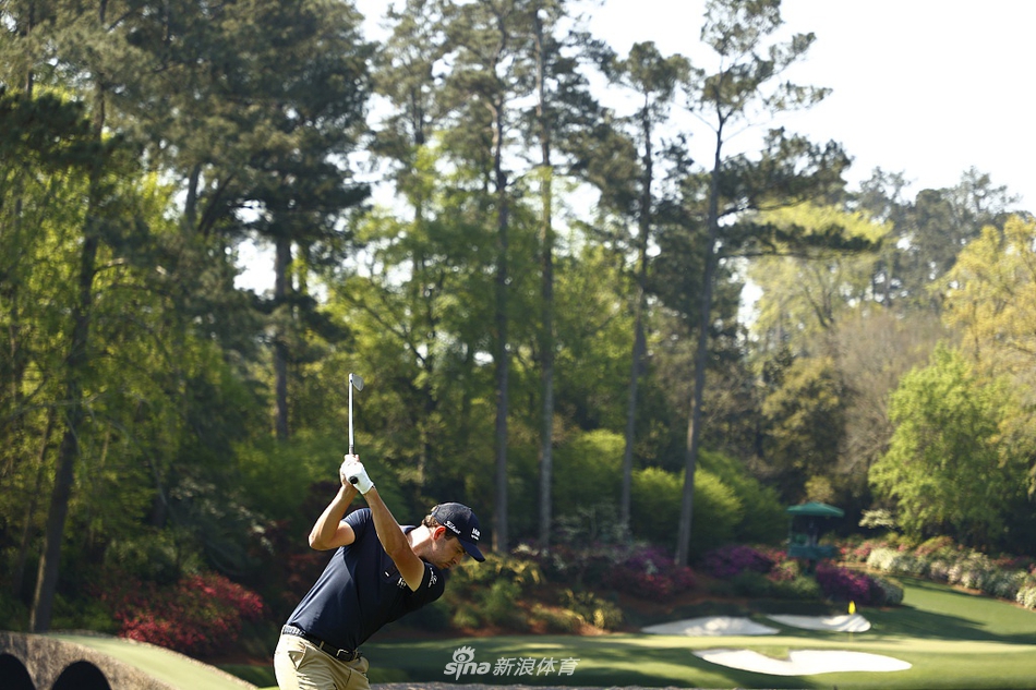 球员穿越奥古斯塔盛开的杜鹃花丛，粉色花海与翠绿球场相映成趣