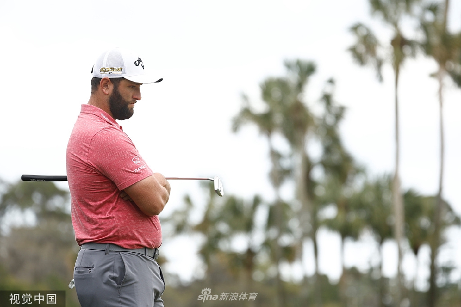 细雨朦胧中，一位球员的球童正用毛巾仔细擦拭球杆，雨伞下的他们专注而平静，展现了职业高尔夫的另一面。