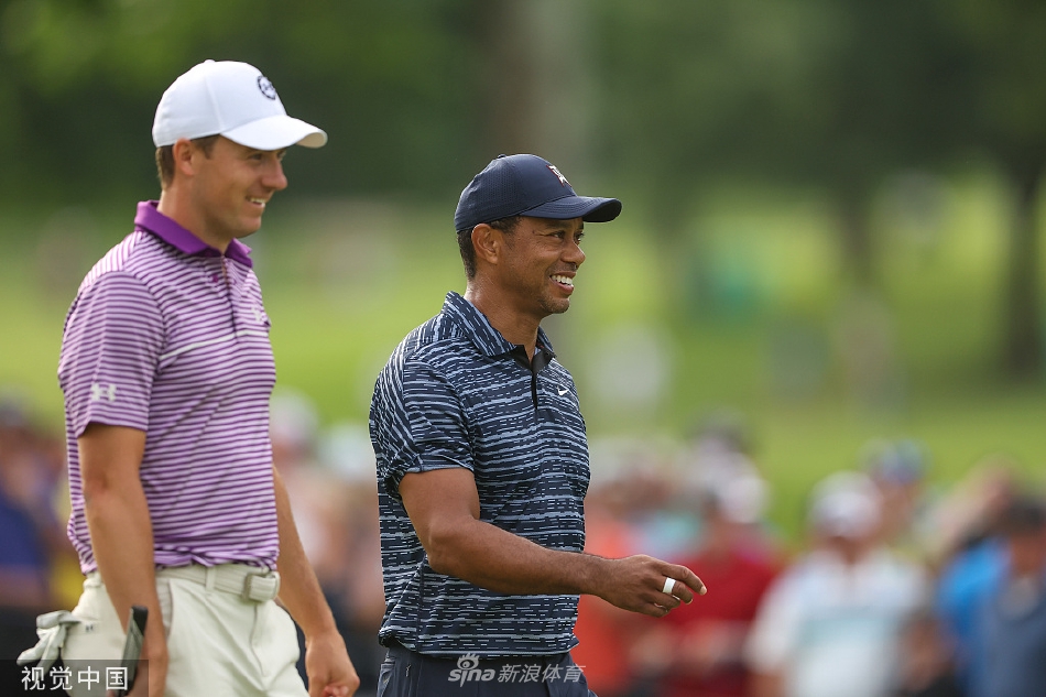 伍兹与球童讨论选杆，两人专注交流，展现出团队合作与赛场上的严谨态度。