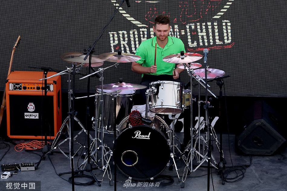 丹尼尔·加文斯高举冠军奖杯向观众致意，背景是庆祝的彩花与热情的球迷，气氛达到高潮。