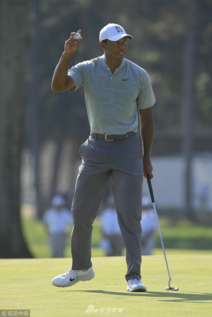 伍兹在观众的簇拥下走向下一个发球台，他微笑着向两侧的球迷挥手致意，场面热烈而温馨。