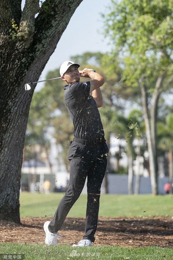 科克面带温暖微笑，亲切地将冠军奖杯递给身旁的球童，分享胜利的荣耀