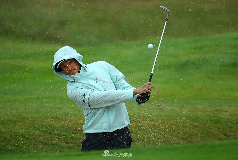 李昊桐身穿红色上衣在练习场挥杆，球杆划破潮湿的空气，动作流畅而充满力量，尽显扎实训练功底。