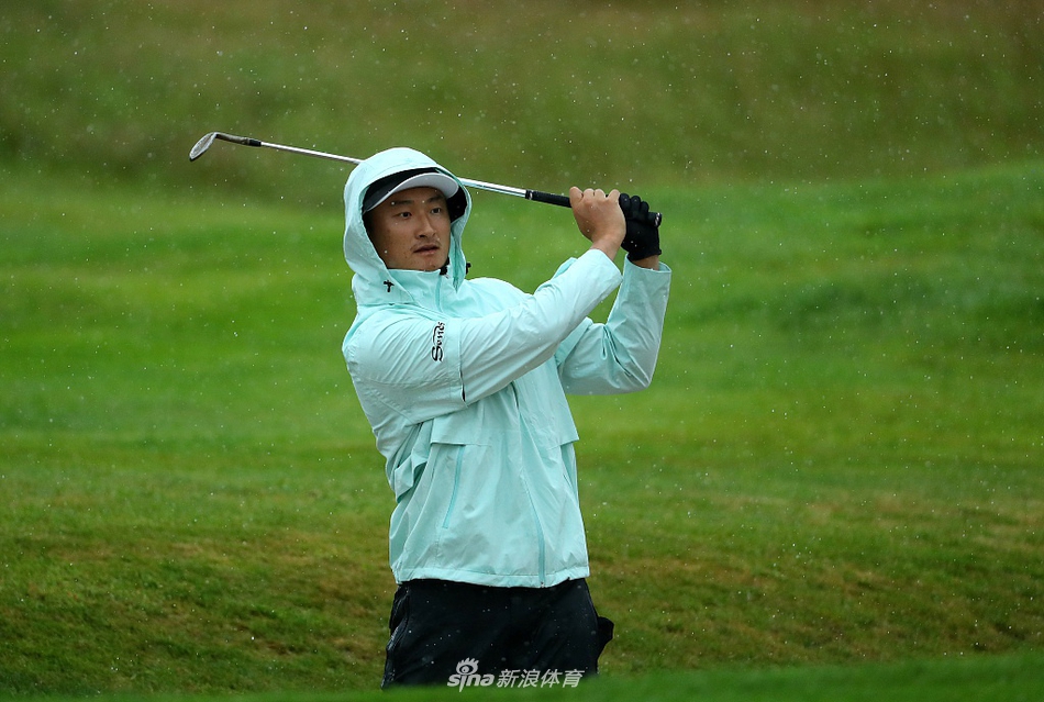 李昊桐在赛场边与教练交流，手指向远方，两人正在认真讨论下一洞的进攻策略与选杆。