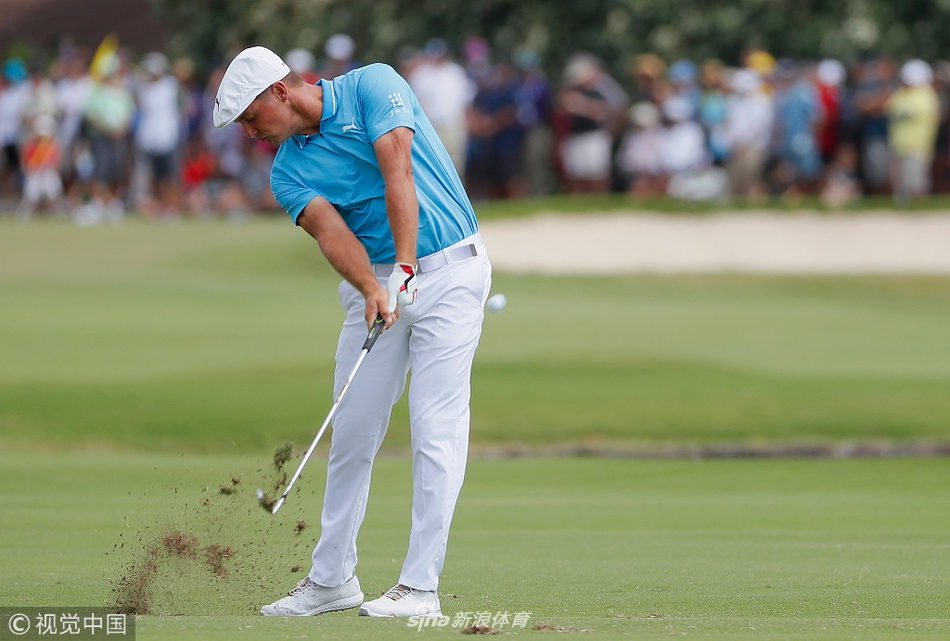 马克·利什曼蹲在果岭边,全神贯注地观察推杆线路的起伏,手中的球标反射着阳光