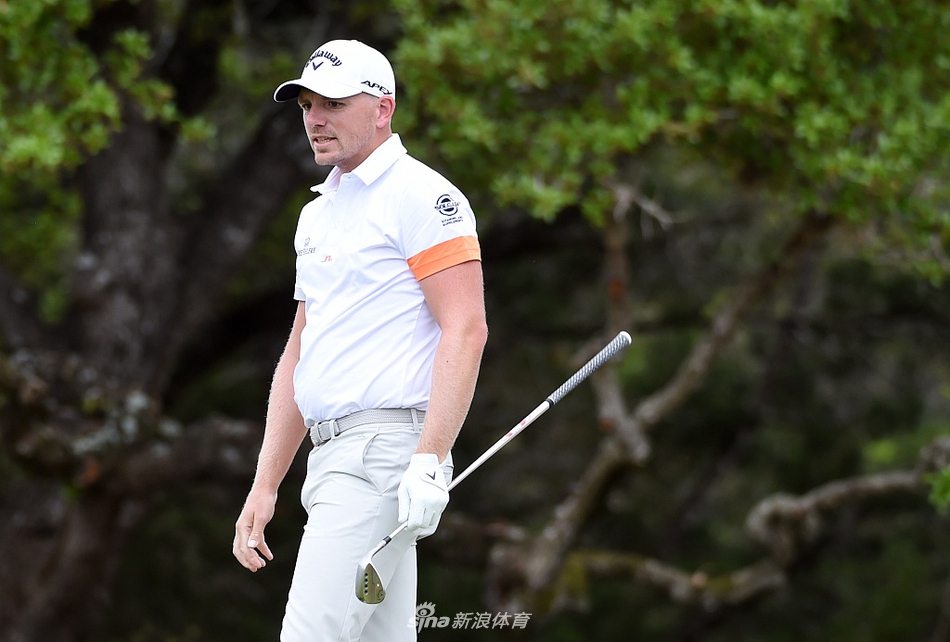 松山英树在球道沙坑中救球，神情冷静专注，沙砾飞扬间展现顶级球员的短杆技巧