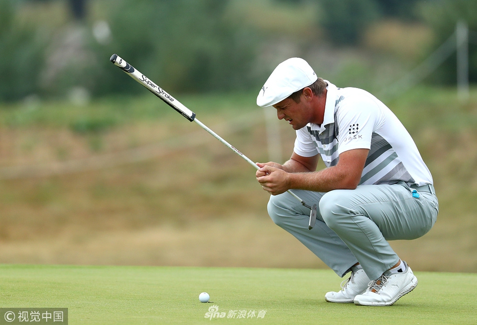 布赖森·德尚博在果岭上俯身，用手指仔细丈量推杆的线路与转折，展现其科学分析型球风。