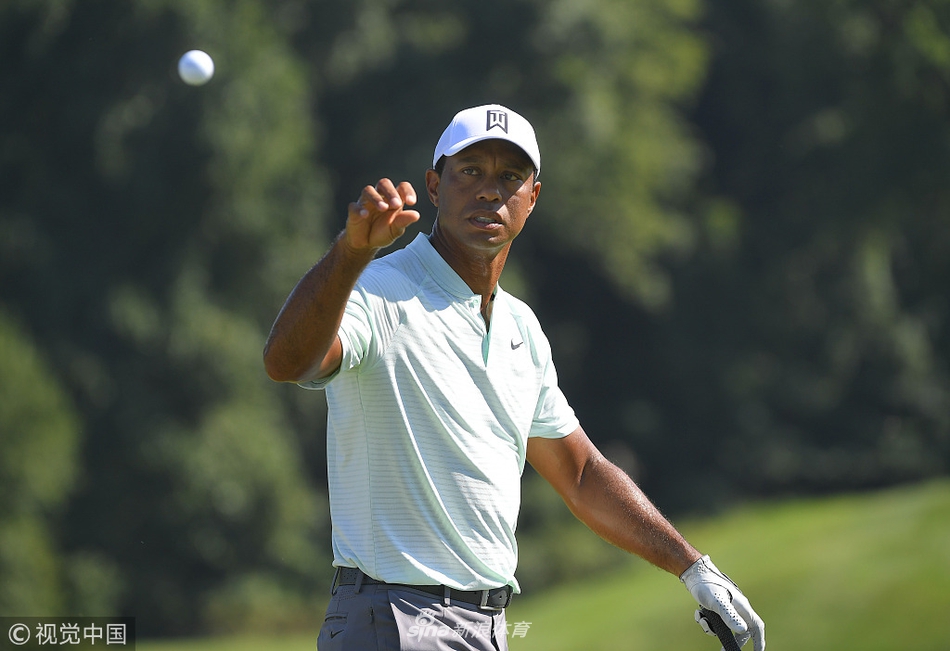 麦克罗伊在果岭上弯腰标记小球的位置，表情认真，他的球童在一旁协助观察果岭起伏。