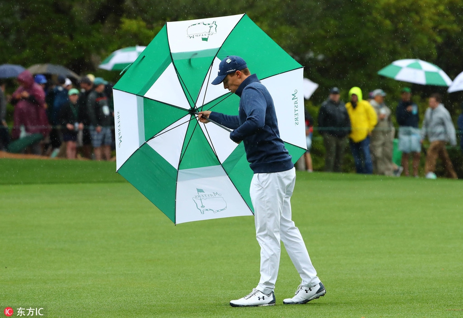 球道旁，两位观众共撑一把大伞，正聚精会神地观看球员击球，伞面的深蓝底色映衬着他们期待的脸庞，展现出风雨无阻的观赛热情。